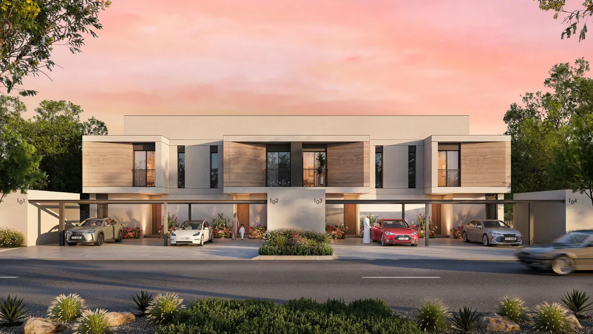A terrace of two-storey Al Ghadeer Parks townhouses under a pink sunset sky